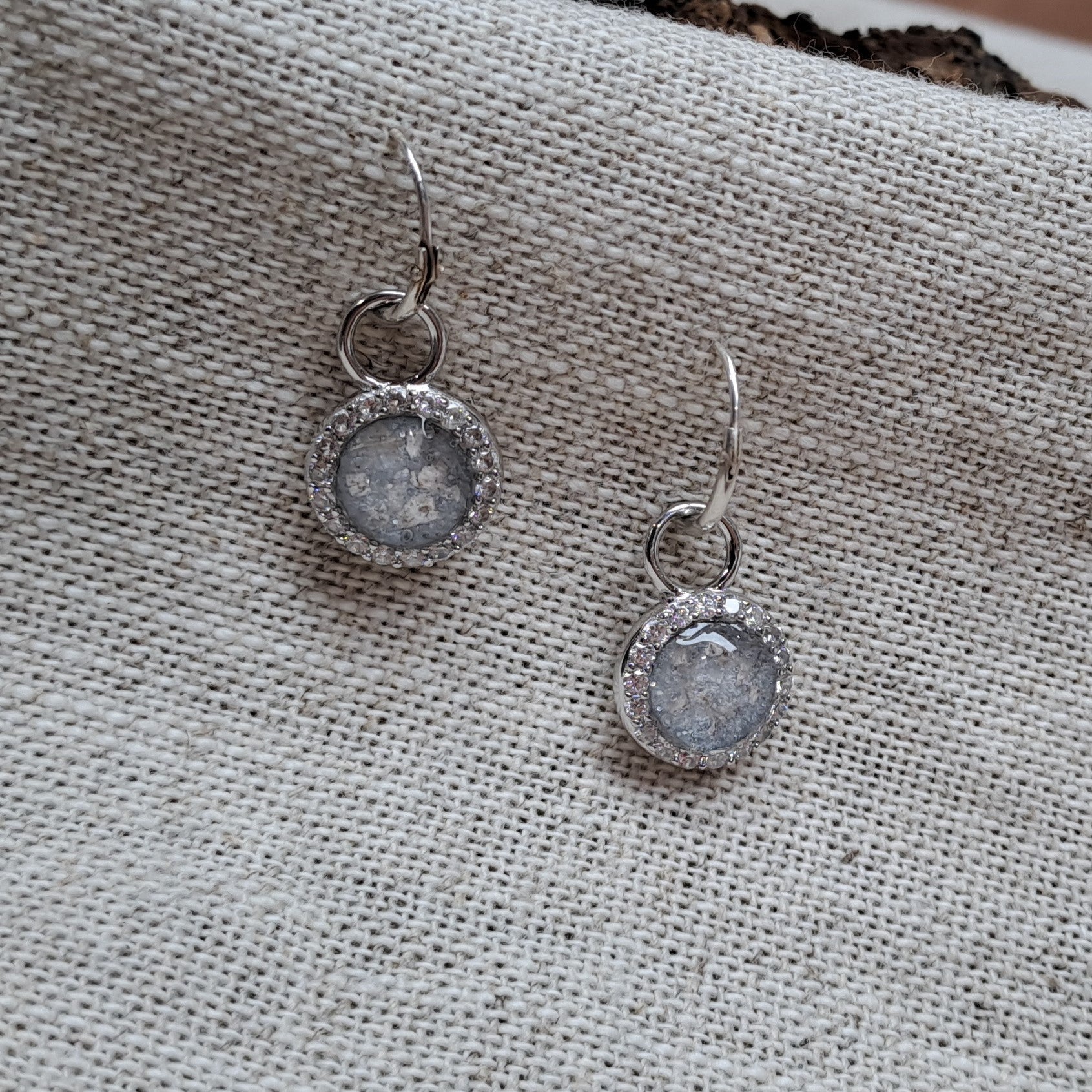 Oorhangers 8 mm diameter, rondom afgewerkt met zirkonia's, aan de voorzijde zichtbaar gevuld met as of haar. alle 