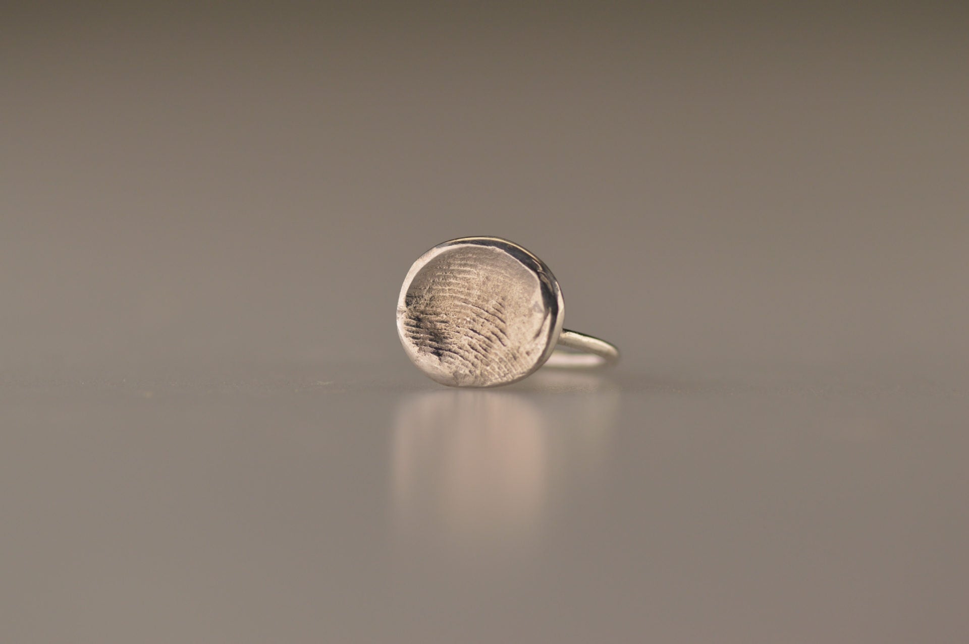 Ring 1.6 mm breed met een iets hollend rond vlak aan de bovenzijde voorzien van een natuurlijke vingerafdruk 