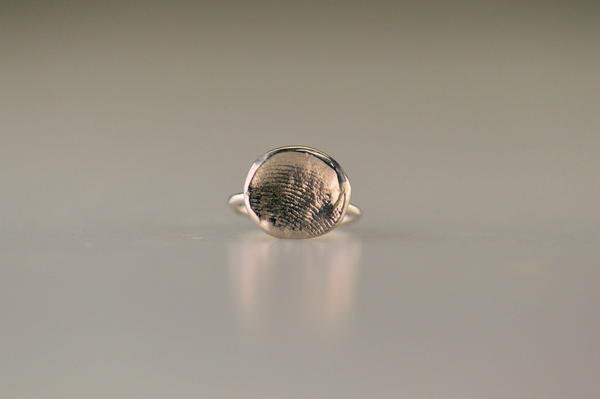 Ring 1.6 mm breed met een iets hollend rond vlak aan de bovenzijde voorzien van een natuurlijke vingerafdruk 