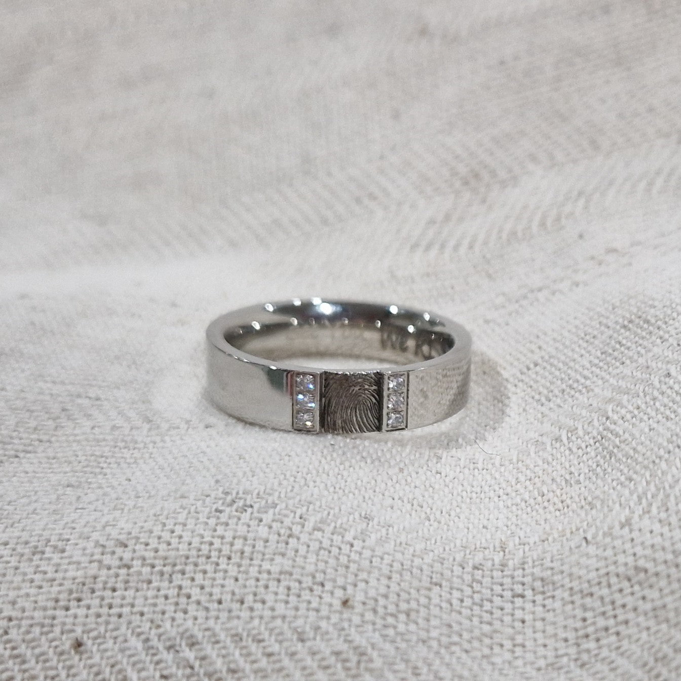 Ring 6 mm aan de bovenzijde voorzien van een vingerafdruk, aan beide zijdes afgewerkt met zirkonia's.  Alle