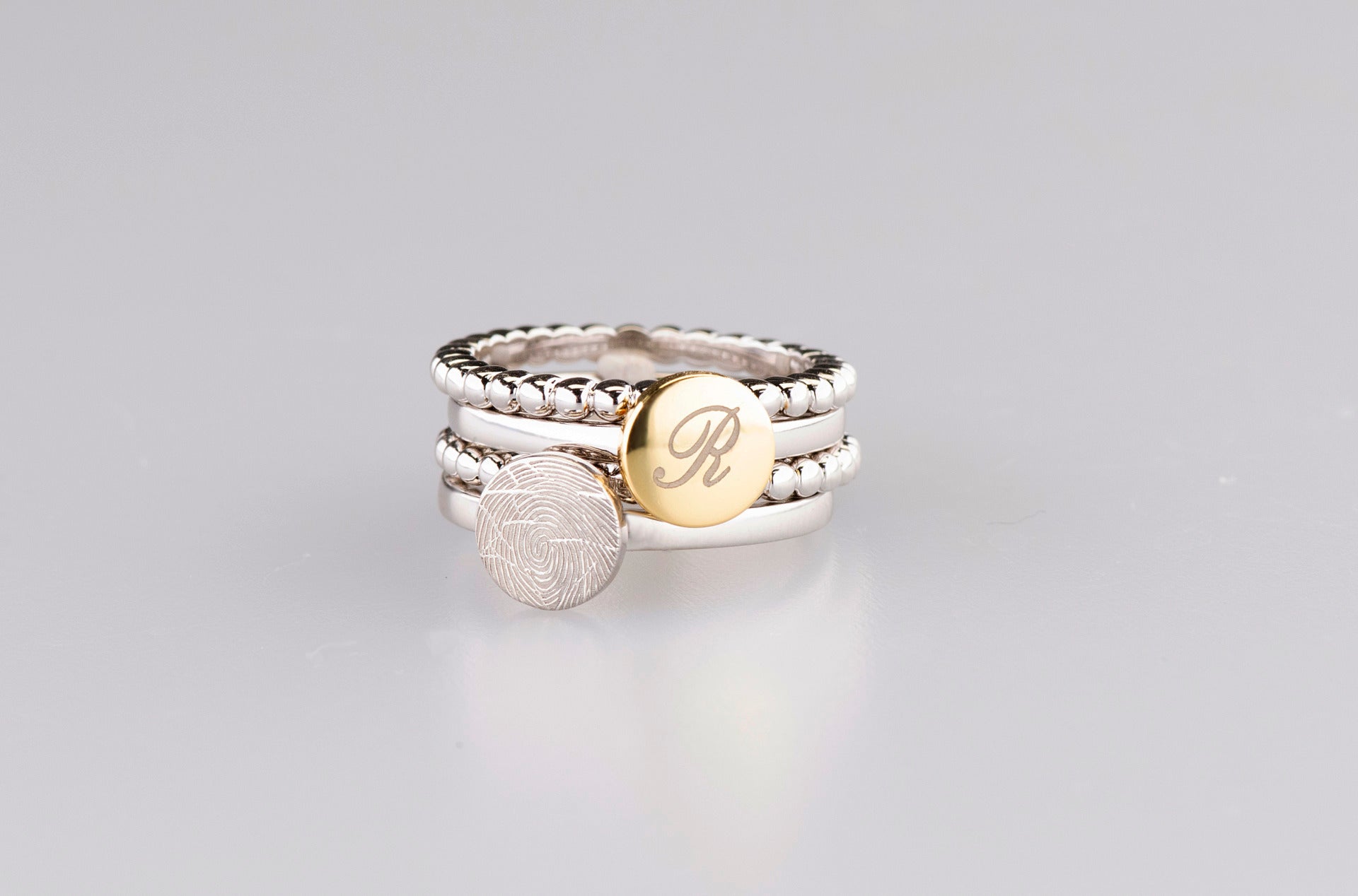 Breedte ringband: 2 mm, Diameter bovenzijde ring: 7.7 mm. Zilveren ring voorzien van een 14 KT gouden vingerafdruk/gravure. Alle