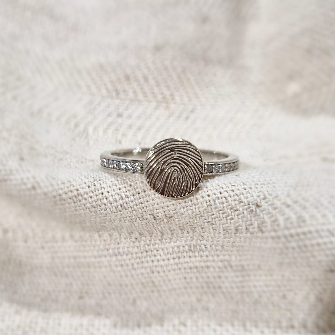 Ring 2 mm breed voorzien van een vingerafdruk/gravure, de ringband is in de bovenste helft afgewerkt met zirkonia's. alle