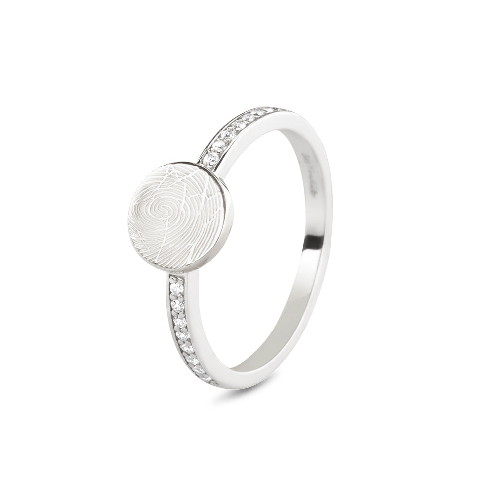 Ring witgoud 2 mm breed voorzien van een vingerafdruk/gravure, de ringband is in de bovenste helft afgewerkt met zirkonia's. witgoud