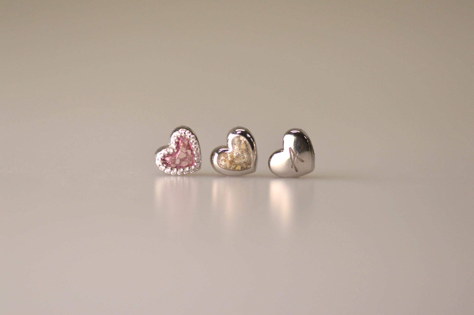 Hartvormige asbedel, het hangoog aan de buitenrand afgewerkt met zirkonia's die aan de voorzijde zichtbaar gevuld wordt met as of haar met een keuze in 20 kleuren.alle