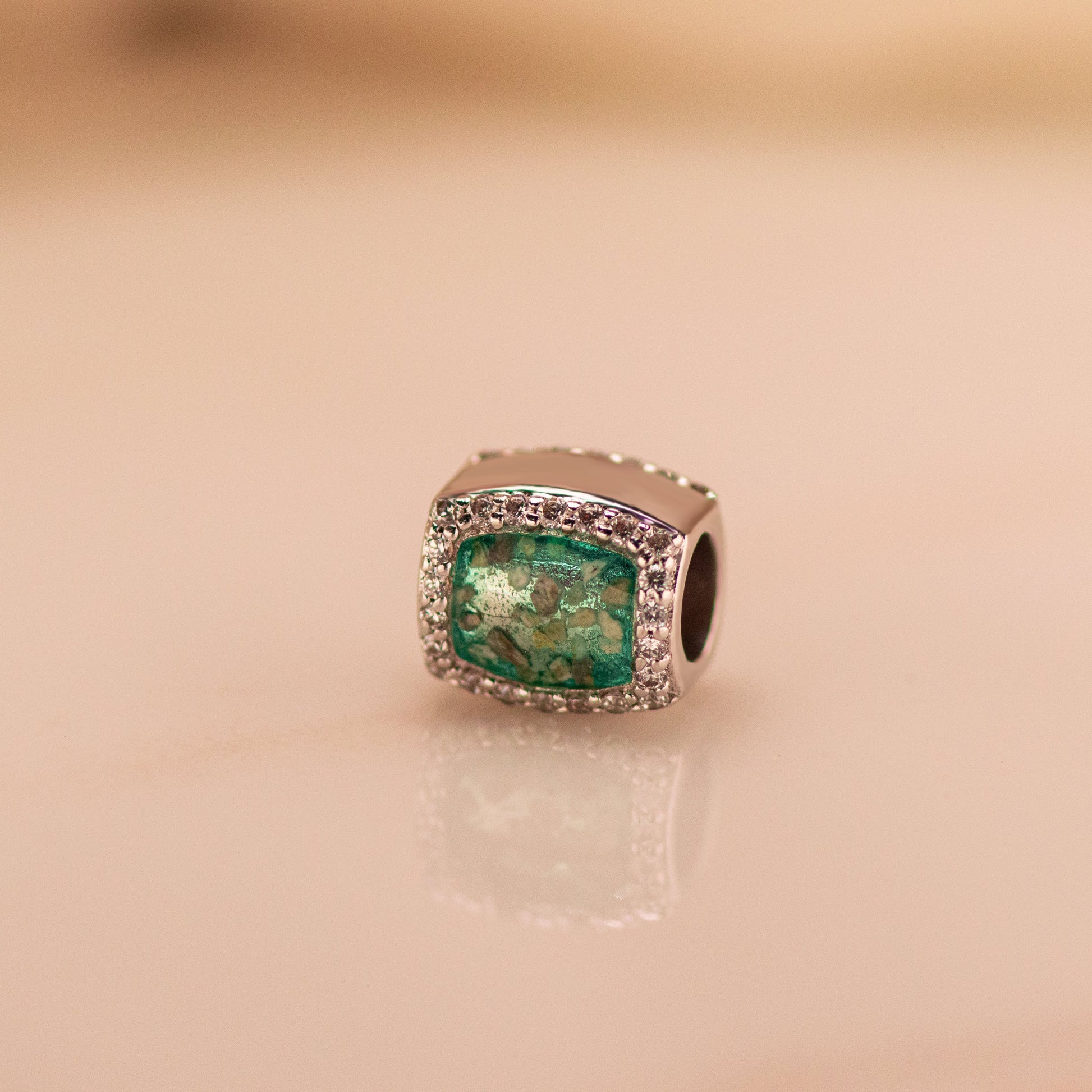 Asbedel rondom afgewerkt met zirkonia's die aan beide zijdes in twee compartimenten zichtbaar gevuld wordt met as of haar.alle