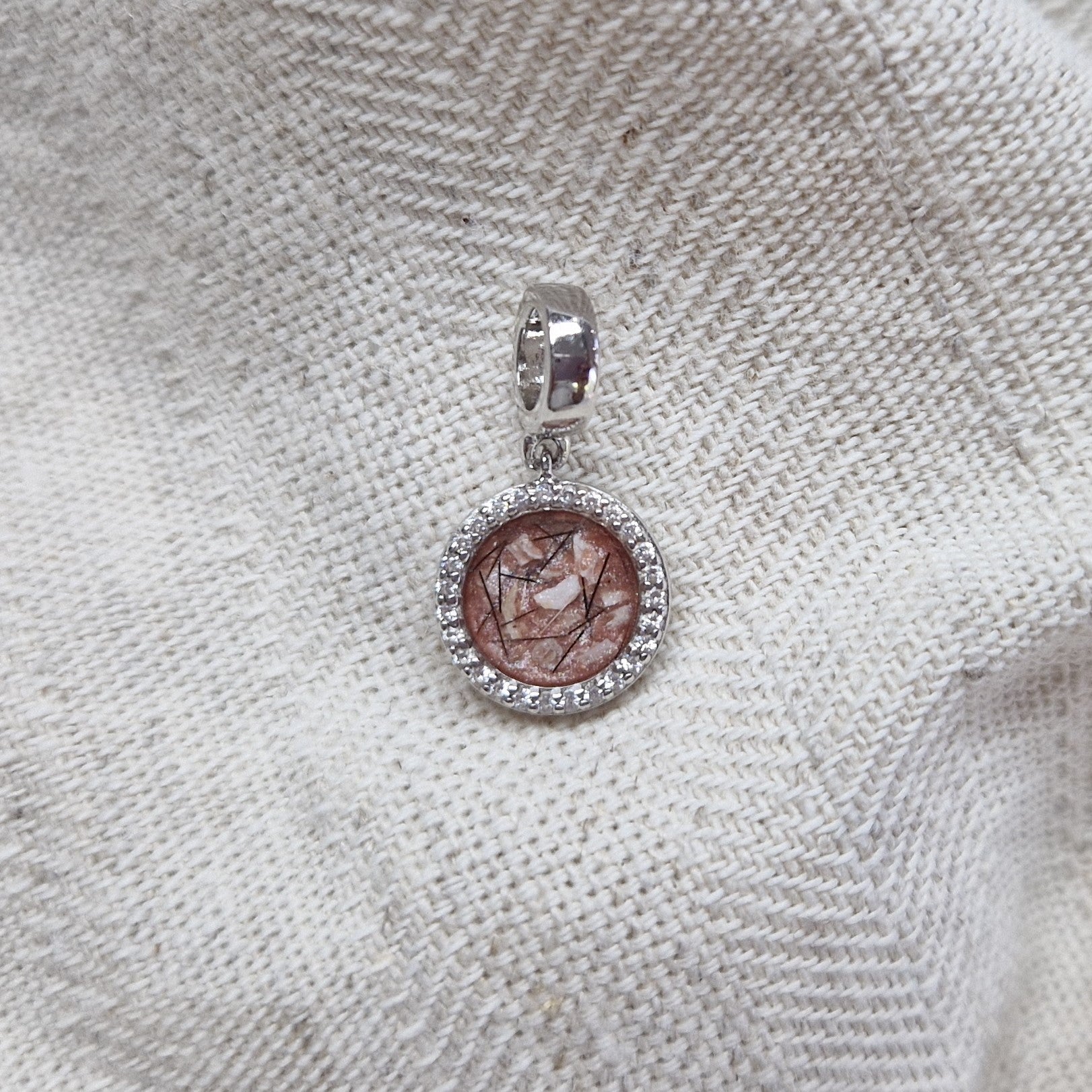 Asbedel, subtiel design rondom afgewerkt met zirkonia's  die aan de voorzijde zichtbaar gevuld wordt met as of haar met een keuze in 20 kleuren.alle