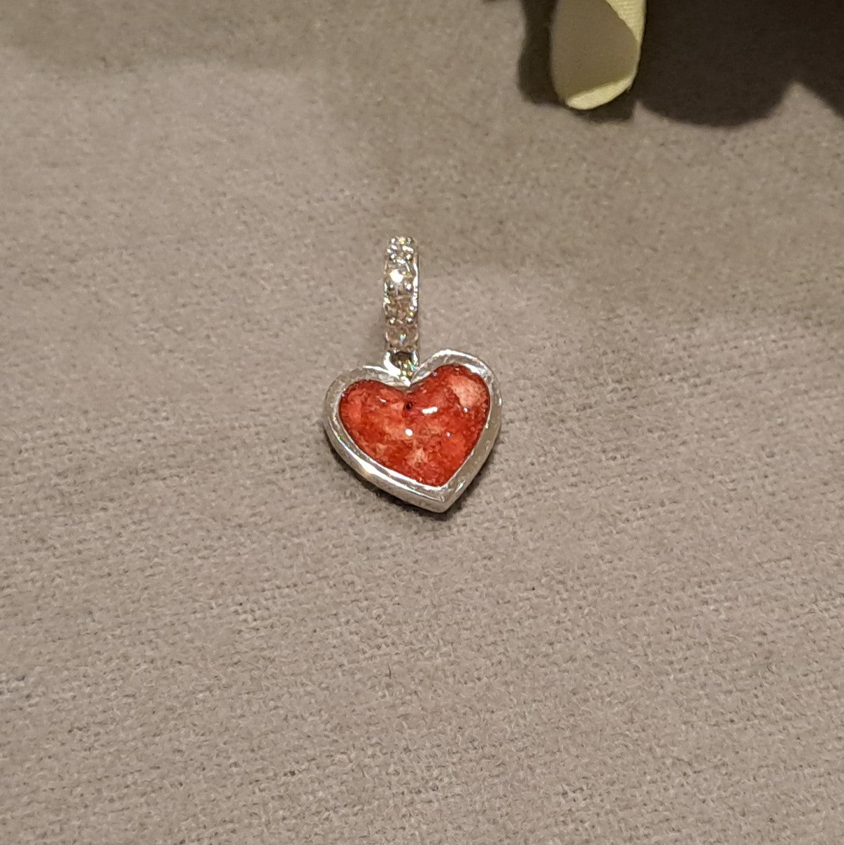 Hartvormige asbedel, het hangoog aan de buitenrand afgewerkt met zirkonia's die aan de voorzijde zichtbaar gevuld wordt met as of haar met een keuze in 20 kleuren.alle