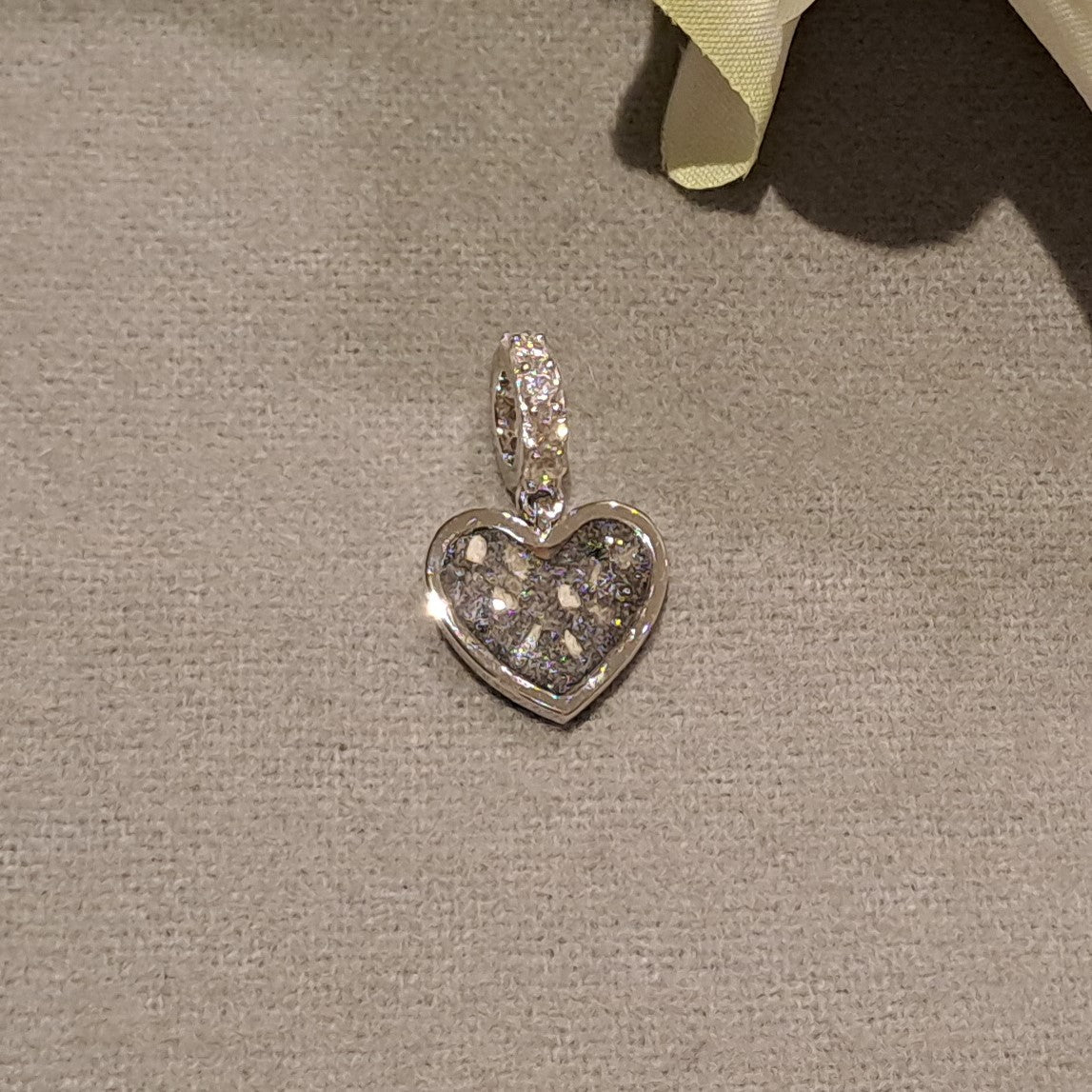 Hartvormige asbedel, het hangoog aan de buitenrand afgewerkt met zirkonia's die aan de voorzijde zichtbaar gevuld wordt met as of haar met een keuze in 20 kleuren.alle