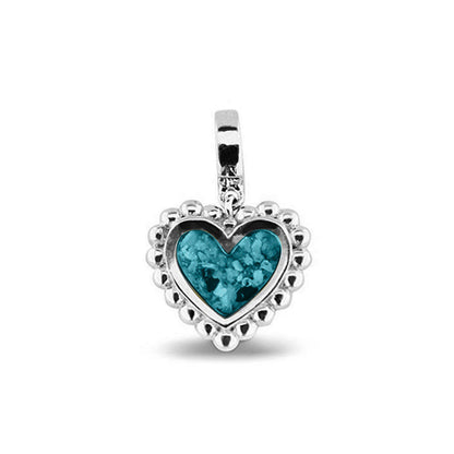 Hartvormige asbedel, die aan de voorzijde zichtbaar gevuld wordt met as of haar. Het vullen en sealen met een keuze in 20 kleuren, wordt in onze ambachtelijke edelsmederij gedaan. Turquoise