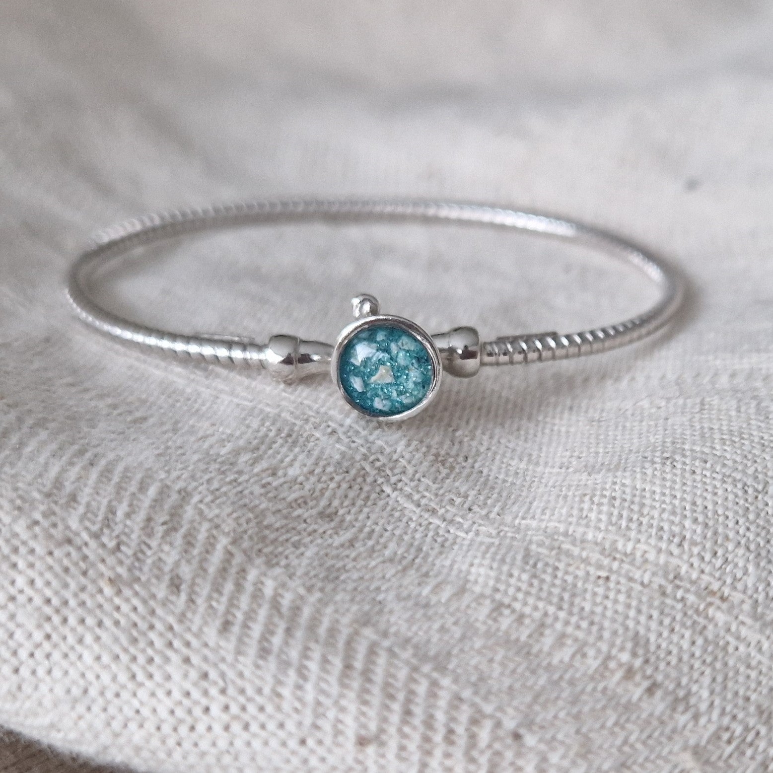 Zilveren as armband met in het midden een ornamentje, gedenksieraad, alle