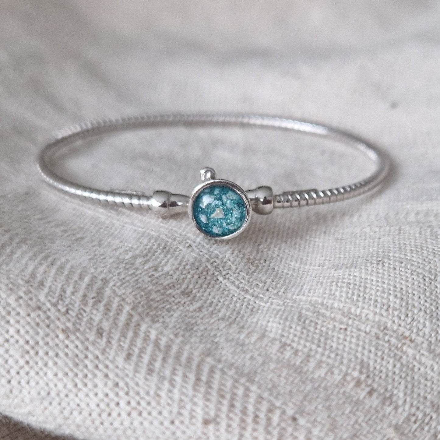 Zilveren as armband met in het midden een ornamentje, gedenksieraad, alle