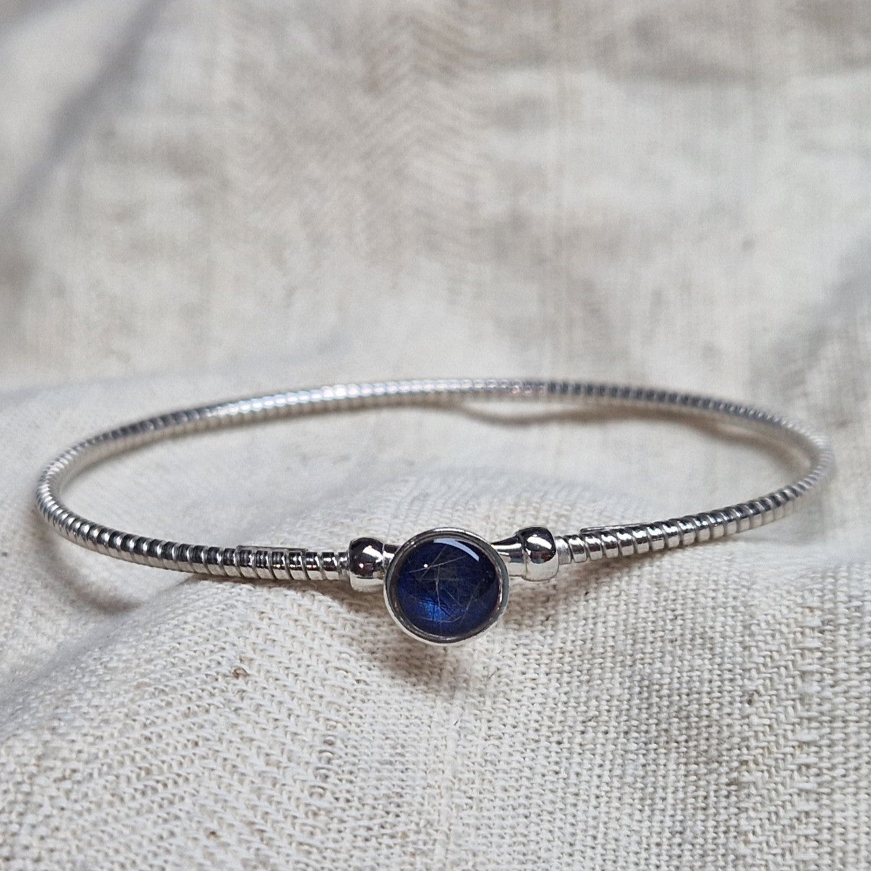 Zilveren as armband met in het midden een ornamentje, gedenksieraad, alle