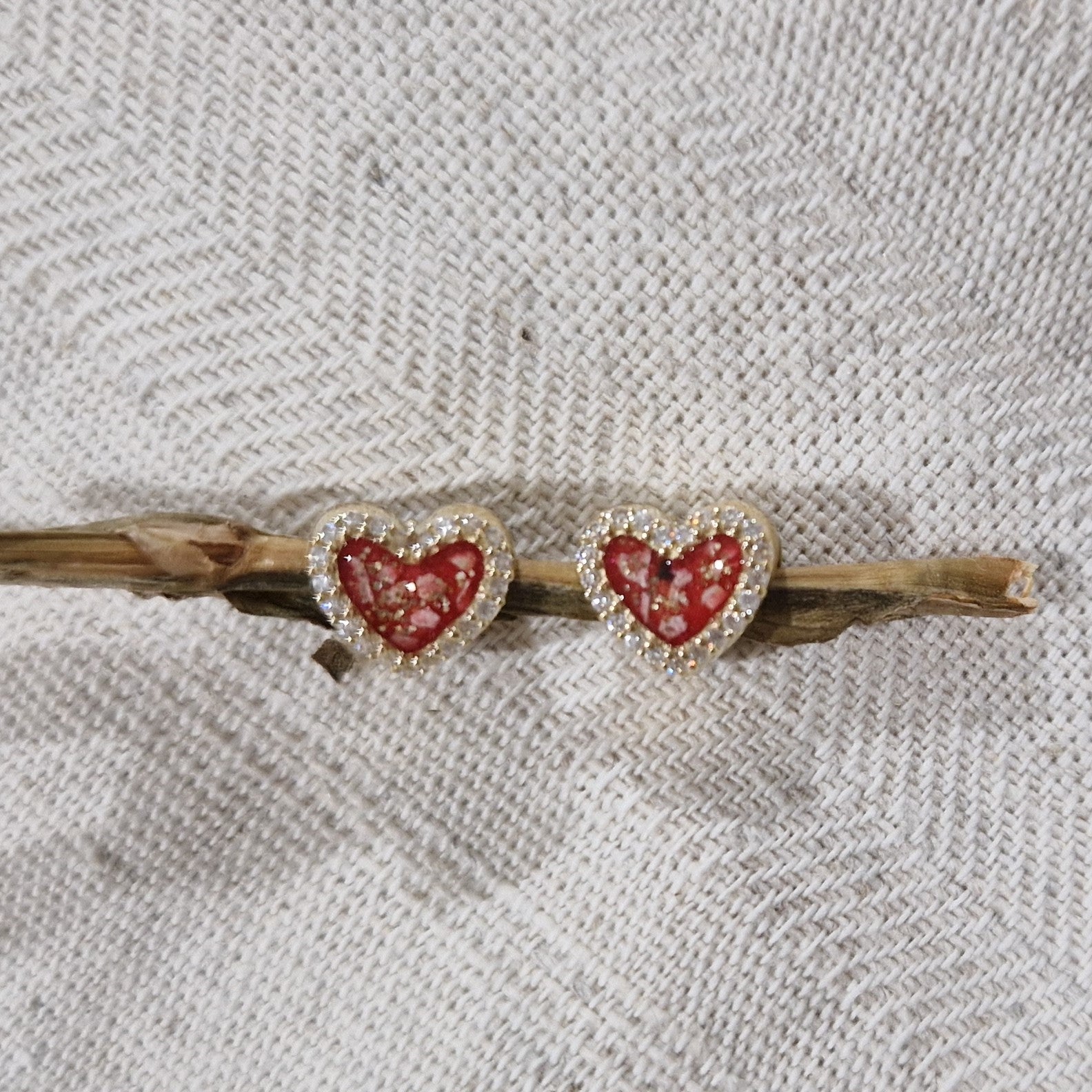 Hartvormige asbedel met  zirkonia's rondom afgewerkt, die aan beide zijdes in twee compartimenten zichtbaar gevuld wordt met as of haar. Alle