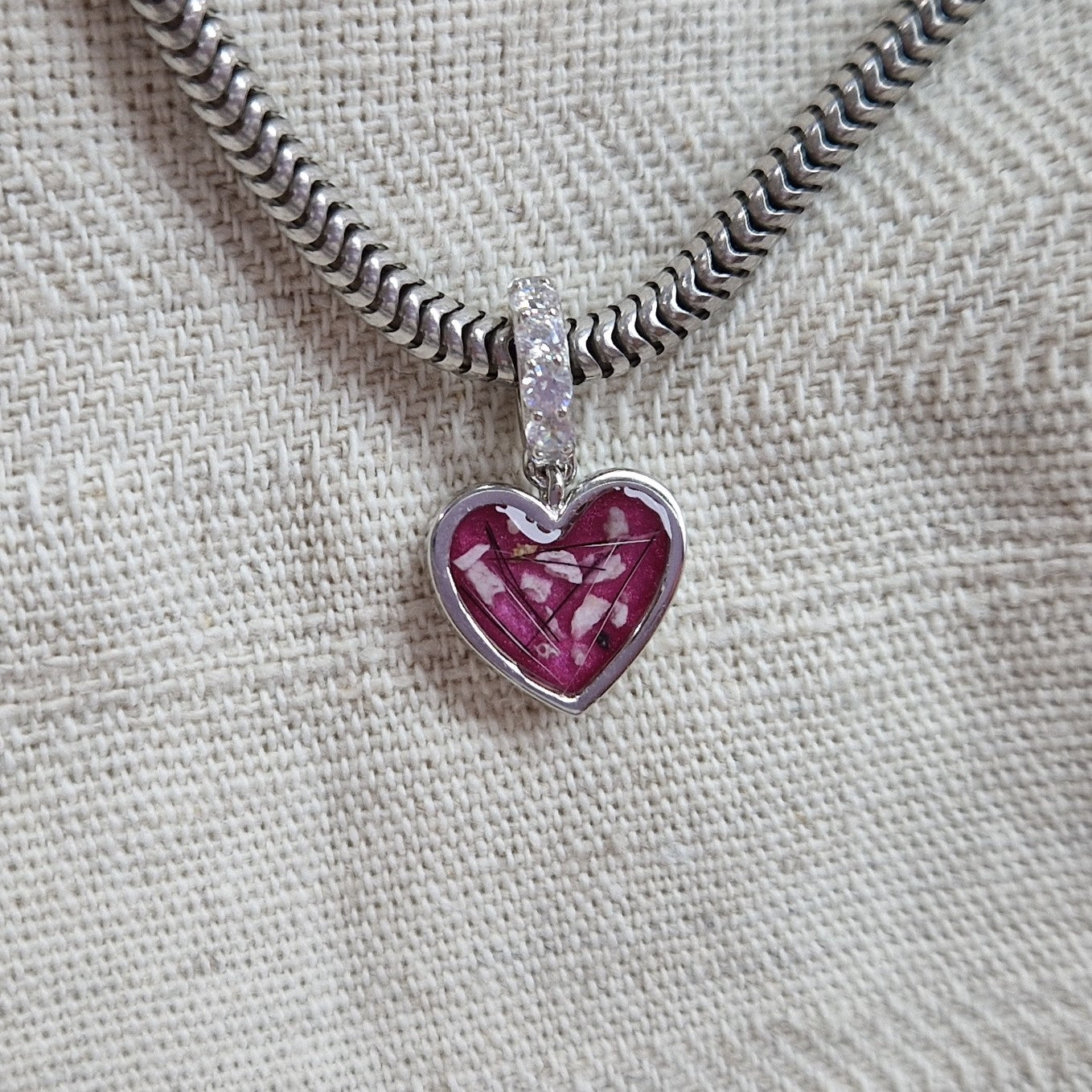 Hartvormige asbedel, het hangoog aan de buitenrand afgewerkt met zirkonia's die aan de voorzijde zichtbaar gevuld wordt met as of haar met een keuze in 20 kleuren.alle