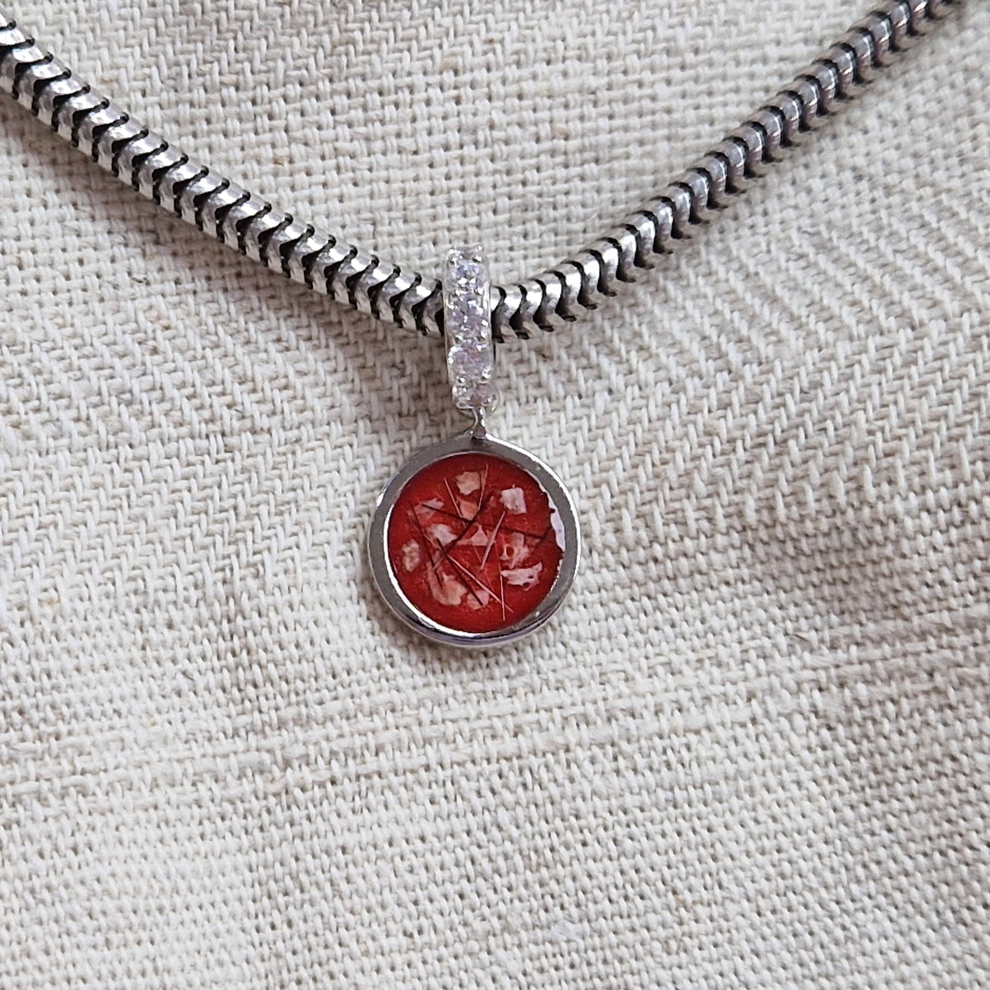 Asbedel rond subtiel design , het hangoog aan de buitenrand afgewerkt met zirkonia's, die aan de voorzijde zichtbaar gevuld wordt met as of haar met een keuze in 20 kleuren. Yellow