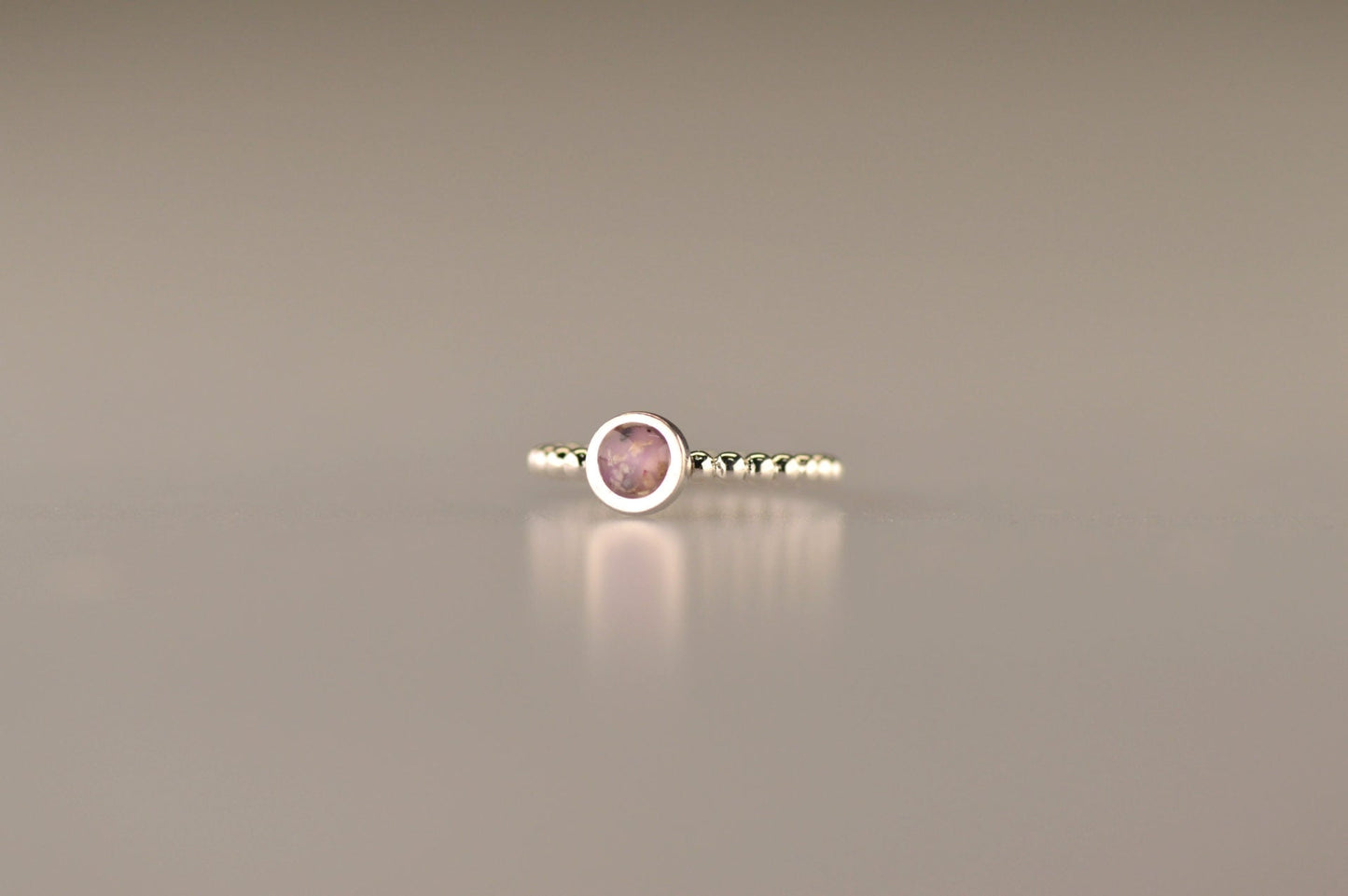 Diameter rondje: 6 mm, Ringband: 2 mm. Ring als gedenksieraad met een rondje er boven op , waar zichtbaar as of haar  in verwerkt wordt. Alle
