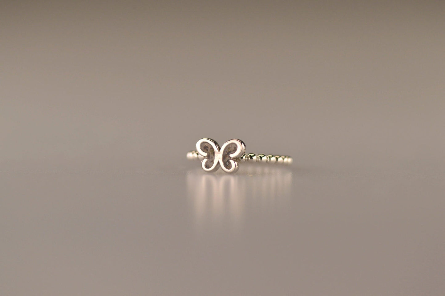 Afmeting vlinder: 8x6 mm, Ringband: 2 mm. Bolletjes ring als gedenksieraad met een vlinder er boven op , waar zichtbaar as of haar  in verwerkt wordt. Alle