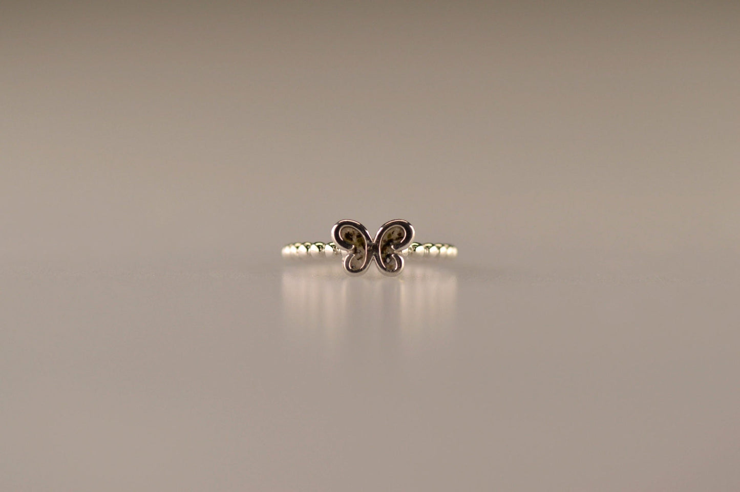 Afmeting vlinder: 8x6 mm, Ringband: 2 mm. Bolletjes ring als gedenksieraad met een vlinder er boven op , waar zichtbaar as of haar  in verwerkt wordt. Alle