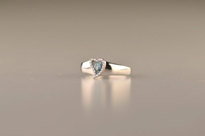 Gedenksieraad, gladde ring waar aan de bovenzijde zichtbaar as of haar verwerkt wordt in een hartje, rondom gezet met zirkonia's of diamanten naar keuze. Alle