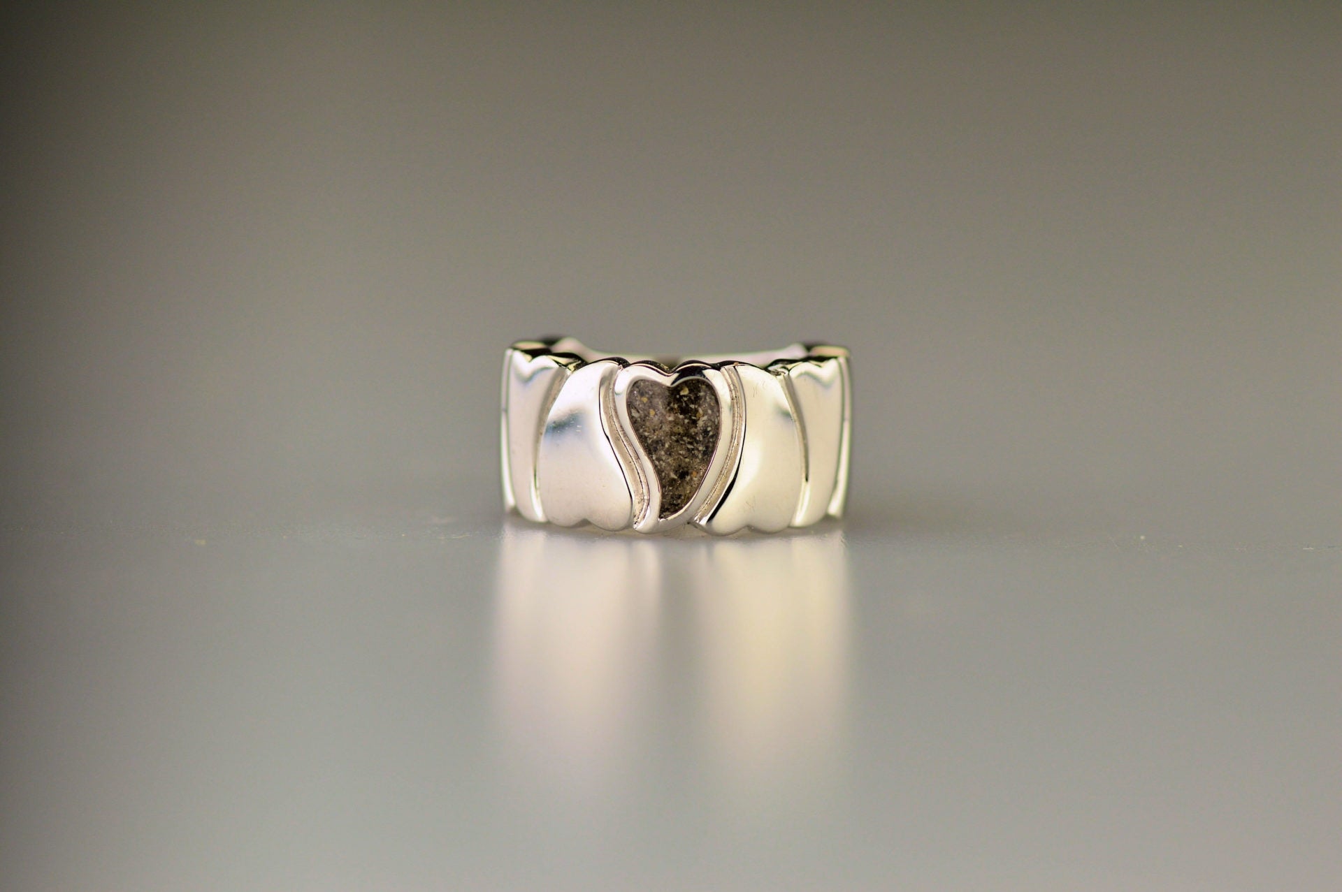 Ring 12 mm uit onze serie gedenksieraden, waar aan de bovenzijde zichtbaar as of haar verwerkt wordt in een hartje. Alle