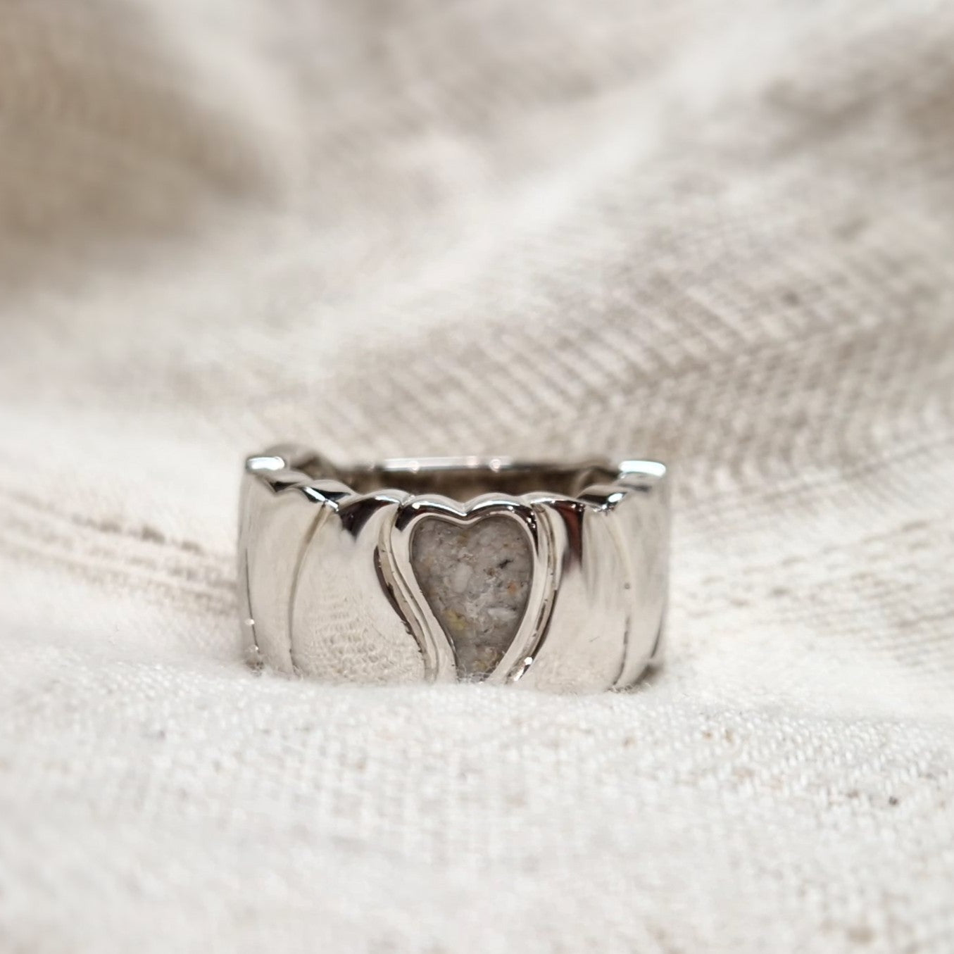 Ring 12 mm uit onze serie gedenksieraden, waar aan de bovenzijde zichtbaar as of haar verwerkt wordt in een hartje. Alle