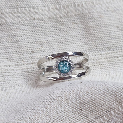 Gedenksieraad, gladde ring waar aan de bovenzijde zichtbaar as of haar (of eventueel melktandjes of moedermelk) verwerkt wordt, rondom gezet met zirkonia's of diamanten naar keuze. Alle