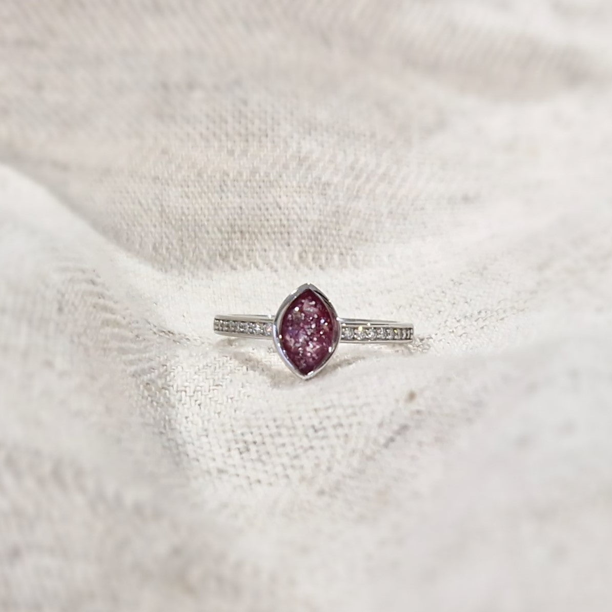 Gedenksieraad, ring 3 mm breed waar aan de bovenzijde zichtbaar as of haar verwerkt wordt. In de ringband zijn subtiel edelstenen naar keuze gezet. Alle