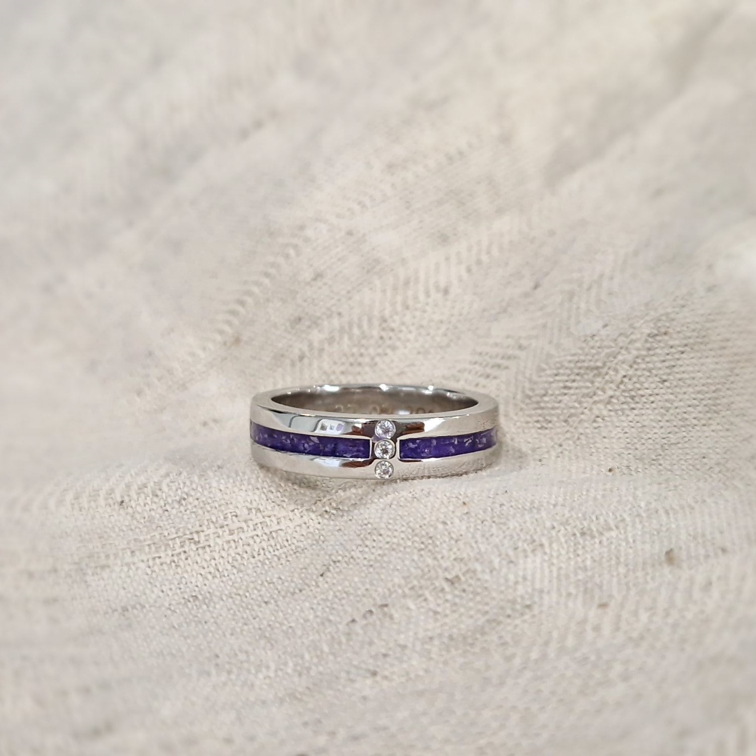 Asring 6 mm uit onze serie gedenksieraden, waar zichtbaar as of haar verwerkt wordt in twee separate compartimenten met in het midden drie stuks zirkonia's of diamanten naar keuze. Alle
