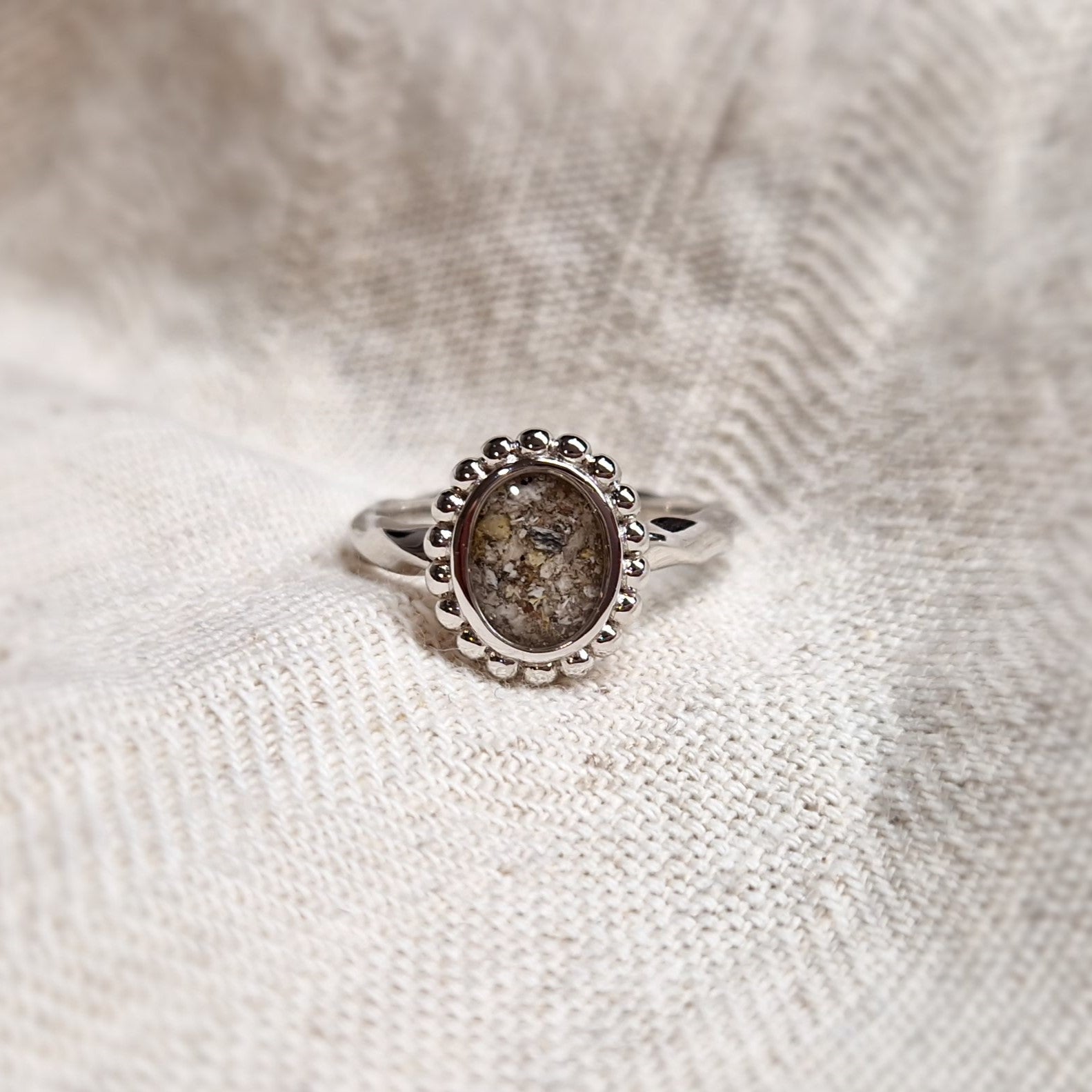 Gedenksieraad, asring met gedraaide scheen waar aan de bovenzijde in ovaalvorm met parelrand zichtbaar as of haar (of eventueel melktandjes of moedermelk) verwerkt wordt. Alle