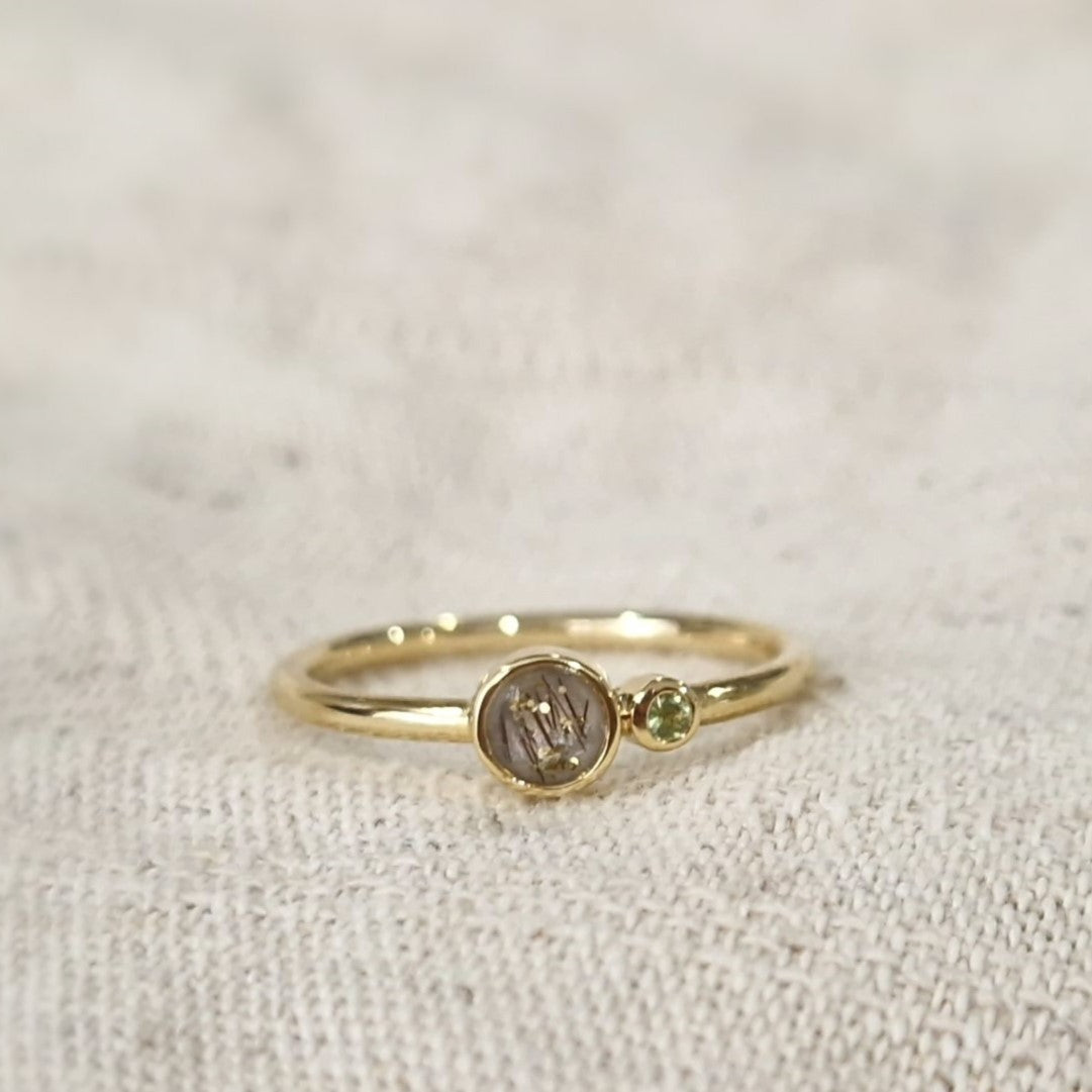 Gedenksieraad waarin een geboortesteen geplaatst wordt naar keuze. Het grotere ronde compartiment van 6 mm wordt zichtbaar gevuld met as,haar of moedermelk. alle