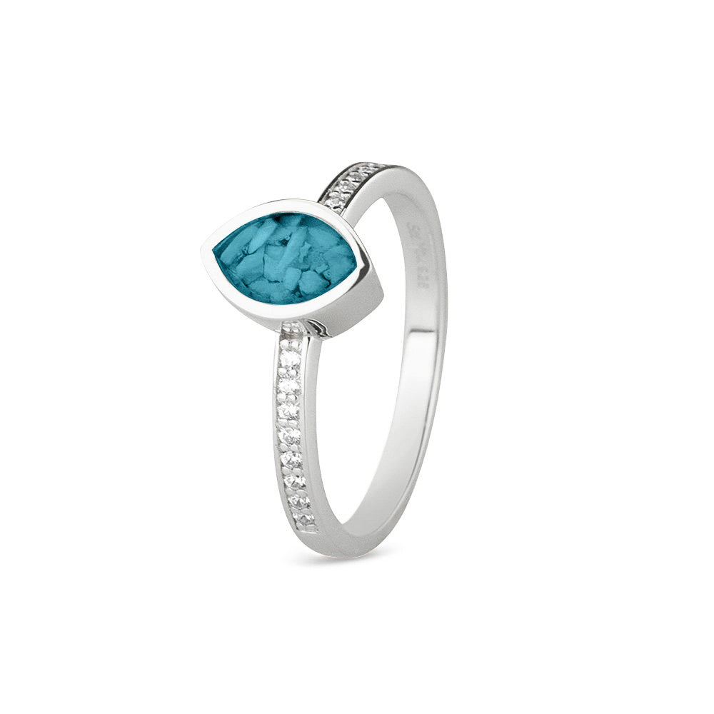 Gedenksieraad, ring 3 mm breed waar aan de bovenzijde zichtbaar as of haar verwerkt wordt. In de ringband zijn subtiel edelstenen naar keuze gezet. Turquoise