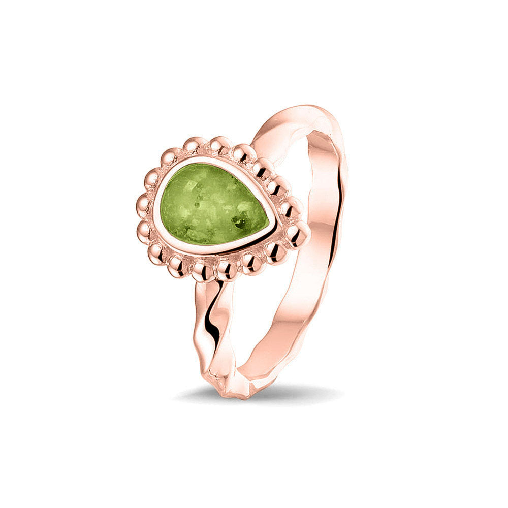 Gedenksieraad, asring met gedraaide scheen waar aan de bovenzijde in druppelvorm met parelrand zichtbaar as of haar (of eventueel melktandjes of moedermelk) verwerkt wordt.green