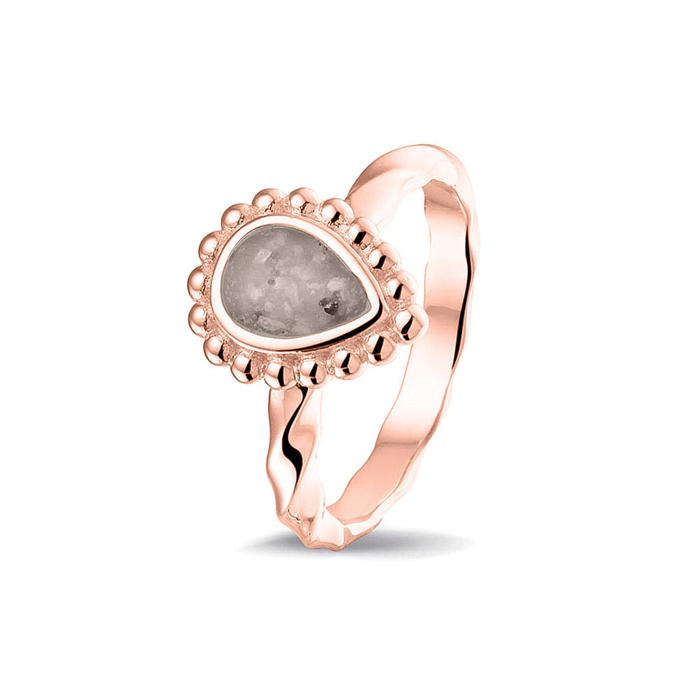 Gedenksieraad, asring met gedraaide scheen waar aan de bovenzijde in druppelvorm met parelrand zichtbaar as of haar (of eventueel melktandjes of moedermelk) verwerkt wordt.silver