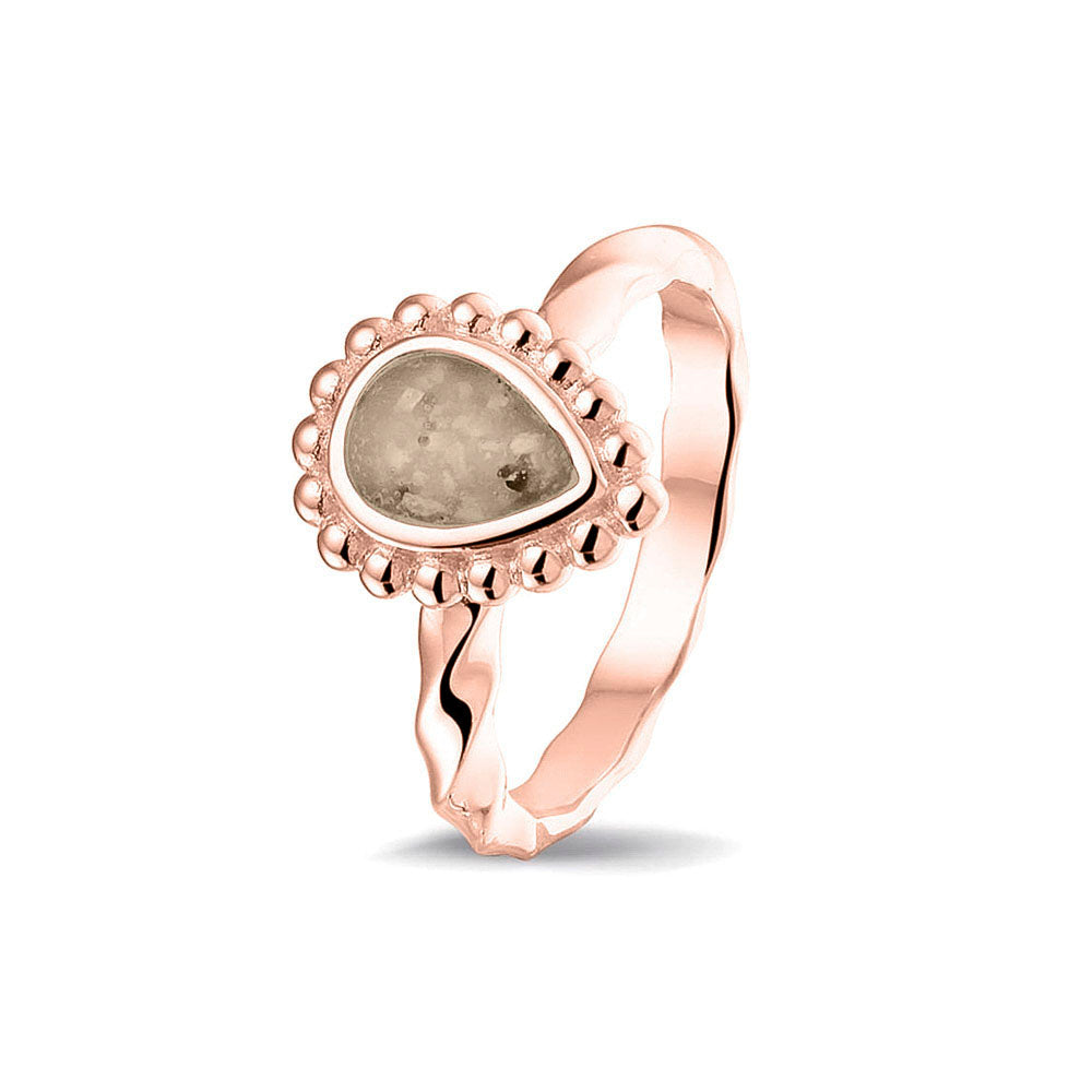 Gedenksieraad, asring met gedraaide scheen waar aan de bovenzijde in druppelvorm met parelrand zichtbaar as of haar (of eventueel melktandjes of moedermelk) verwerkt wordt.transparent