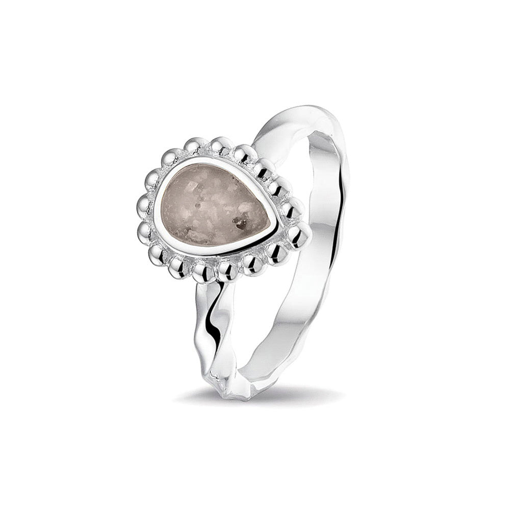 Gedenksieraad, asring met gedraaide scheen waar aan de bovenzijde in druppelvorm met parelrand zichtbaar as of haar (of eventueel melktandjes of moedermelk) verwerkt wordt.silver