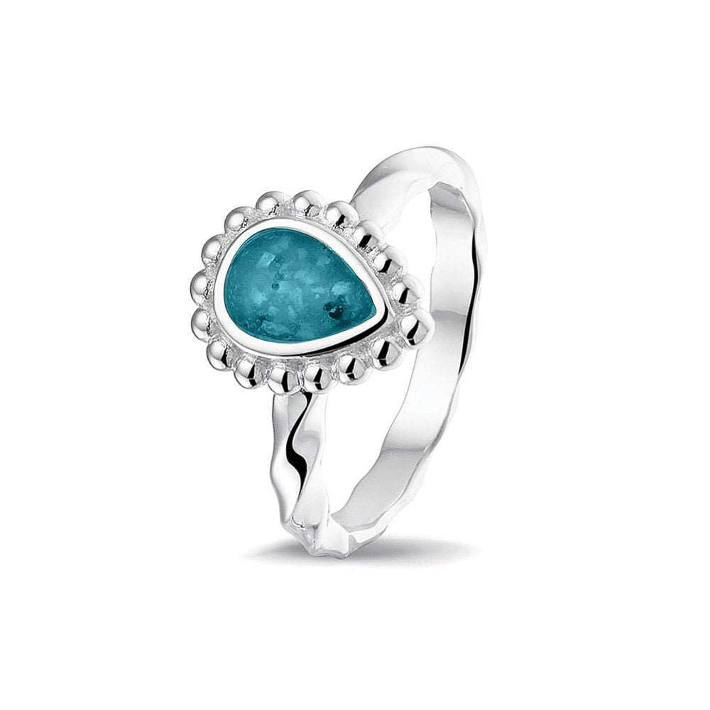Gedenksieraad, asring met gedraaide scheen waar aan de bovenzijde in druppelvorm met parelrand zichtbaar as of haar (of eventueel melktandjes of moedermelk) verwerkt wordt.turquoise