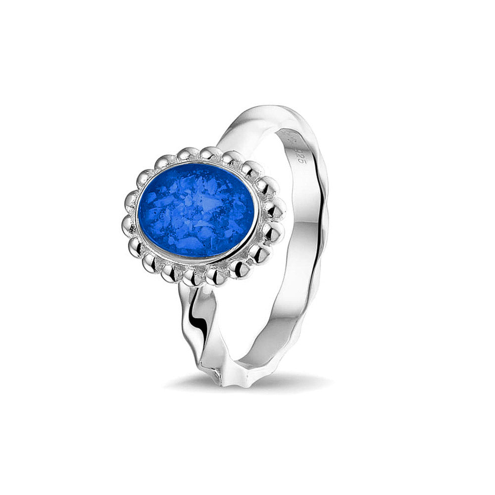 Gedenksieraad, asring met gedraaide scheen waar aan de bovenzijde in druppelvorm met parelrand zichtbaar as of haar (of eventueel melktandjes of moedermelk) verwerkt wordt. Blue