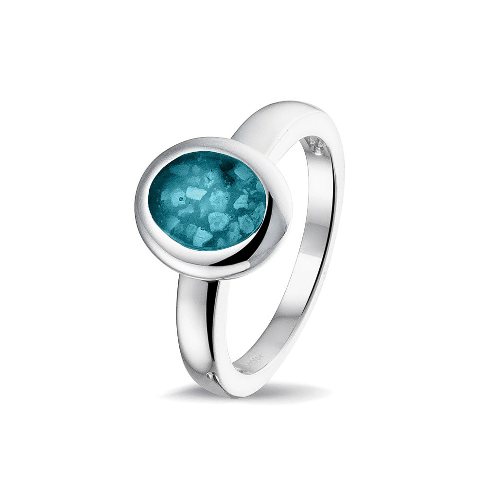 Gedenksieraad, gladde ring 3 mm waar aan de ovale bovenzijde zichtbaar as of haar (of eventueel melktandjes of moedermelk) verwerkt wordt. Turquoise