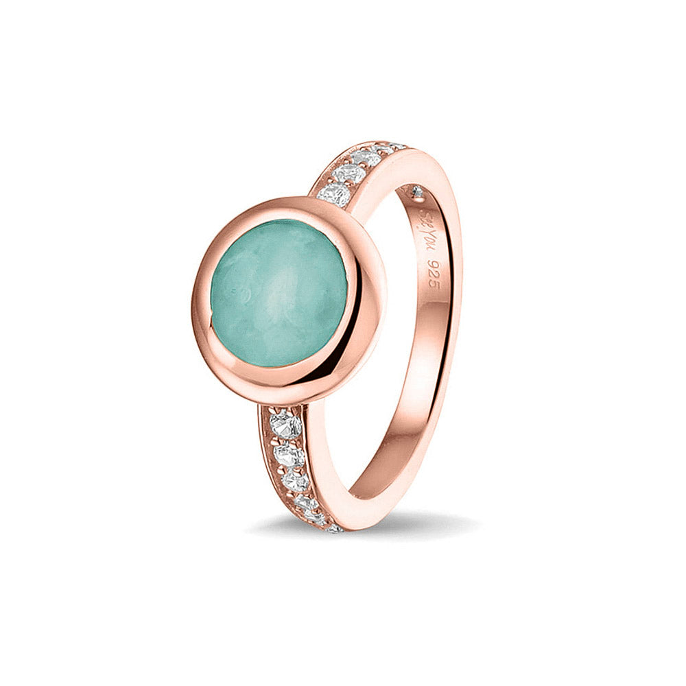 Gedenksieraad, ring 3 mm waar aan de bovenzijde zichtbaar as of haar verwerkt wordt. In de bovenste helft van de ringband zijn zirkonia's of diamanten naar keuze gezet.  Aqua