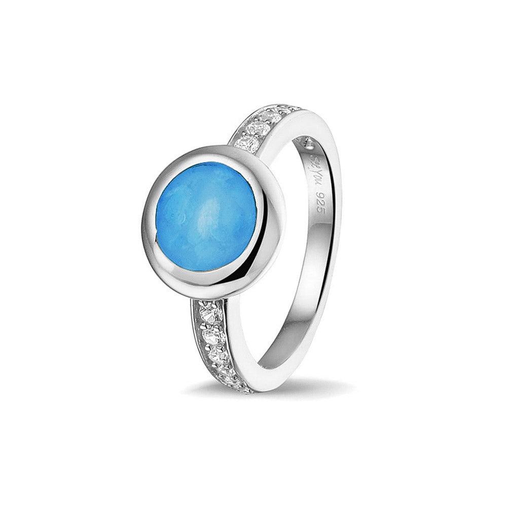 Gedenksieraad, ring 3 mm waar aan de bovenzijde zichtbaar as of haar verwerkt wordt. In de bovenste helft van de ringband zijn zirkonia's of diamanten naar keuze gezet.  Marine