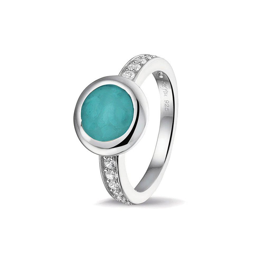 Gedenksieraad, ring 3 mm waar aan de bovenzijde zichtbaar as of haar verwerkt wordt. In de bovenste helft van de ringband zijn zirkonia's of diamanten naar keuze gezet.  Turquoise