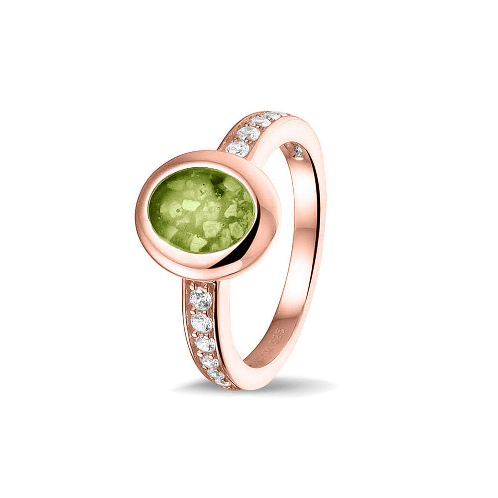 Gedenksieraad, ring 3 mm waar aan de ovale bovenzijde zichtbaar as of haar verwerkt wordt. In de bovenste helft van de ringband zijn zirkonia's of diamanten naar keuze gezet. Green
