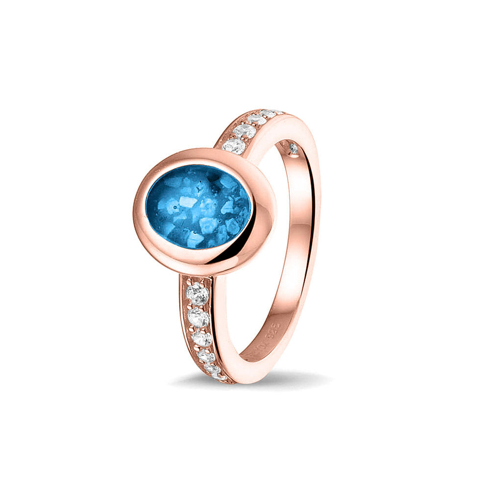 Gedenksieraad, ring 3 mm waar aan de ovale bovenzijde zichtbaar as of haar verwerkt wordt. In de bovenste helft van de ringband zijn zirkonia's of diamanten naar keuze gezet. Marine