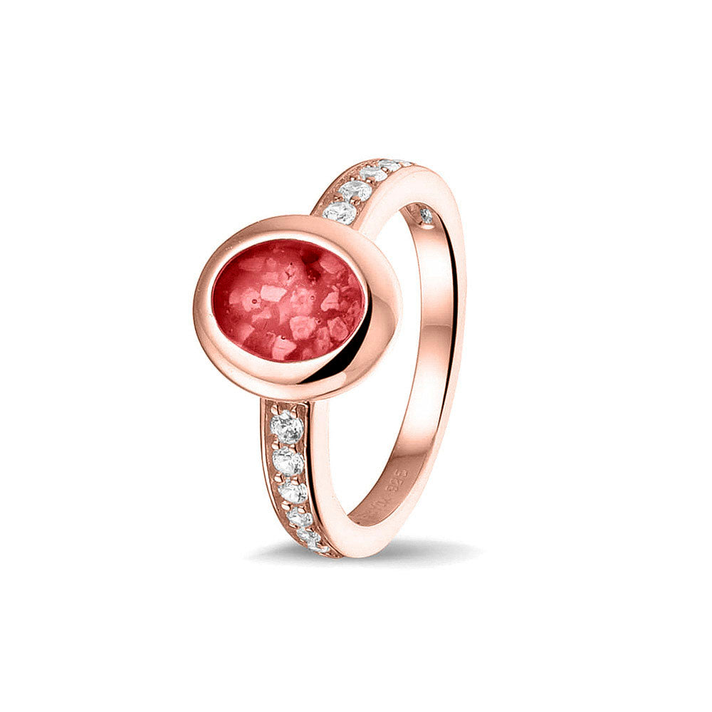 Gedenksieraad, ring 3 mm waar aan de ovale bovenzijde zichtbaar as of haar verwerkt wordt. In de bovenste helft van de ringband zijn zirkonia's of diamanten naar keuze gezet. Red