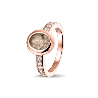 Gedenksieraad, ring 3 mm waar aan de ovale bovenzijde zichtbaar as of haar verwerkt wordt. In de bovenste helft van de ringband zijn zirkonia's of diamanten naar keuze gezet. Transparent