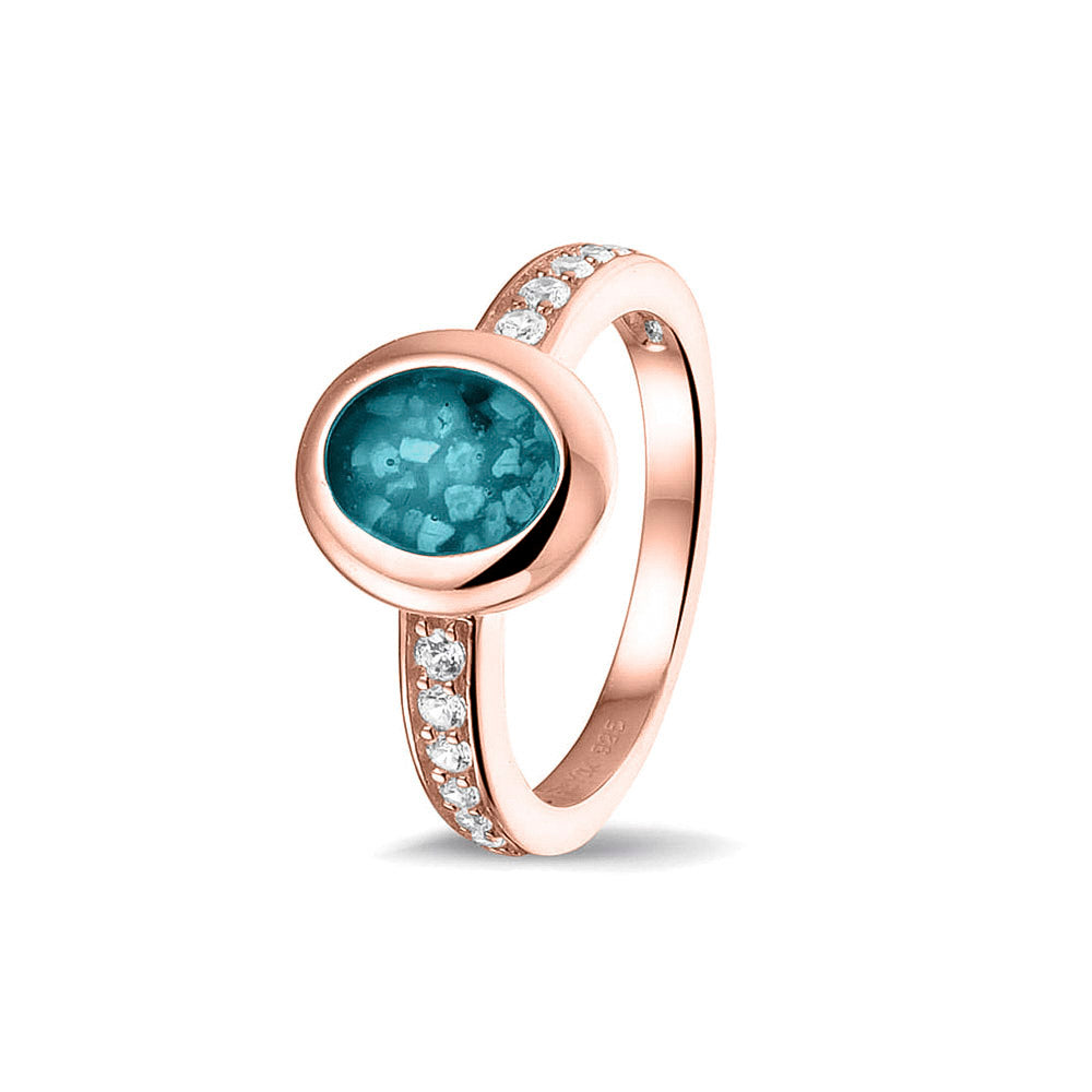 Gedenksieraad, ring 3 mm waar aan de ovale bovenzijde zichtbaar as of haar verwerkt wordt. In de bovenste helft van de ringband zijn zirkonia's of diamanten naar keuze gezet. Turquoise
