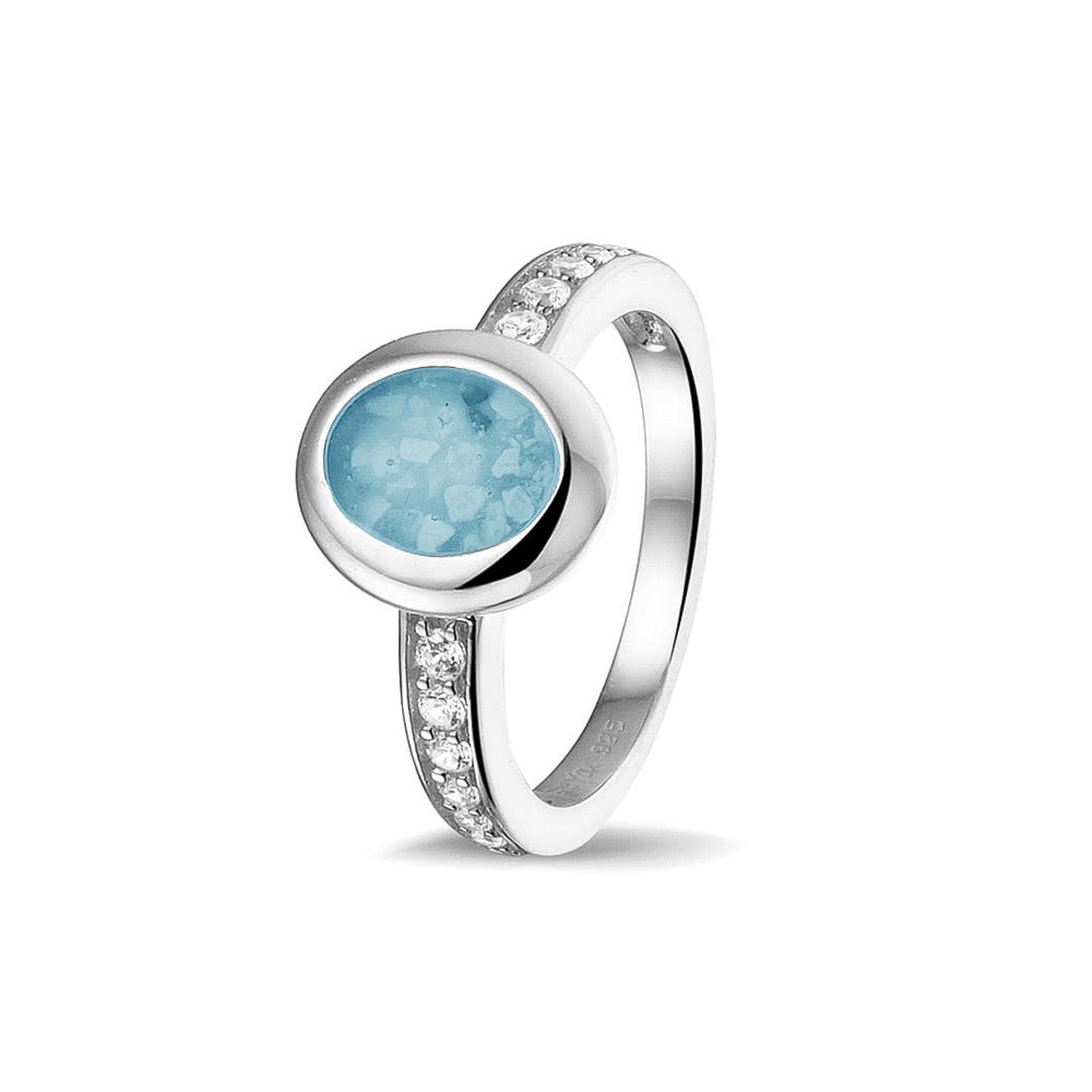 Gedenksieraad, ring 3 mm waar aan de ovale bovenzijde zichtbaar as of haar verwerkt wordt. In de bovenste helft van de ringband zijn zirkonia's of diamanten naar keuze gezet. Baby