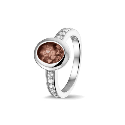 Gedenksieraad, ring 3 mm waar aan de ovale bovenzijde zichtbaar as of haar verwerkt wordt. In de bovenste helft van de ringband zijn zirkonia's of diamanten naar keuze gezet. Brown