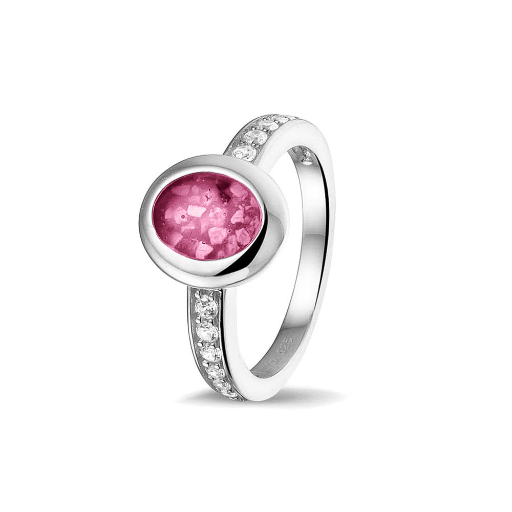 Gedenksieraad, ring 3 mm waar aan de ovale bovenzijde zichtbaar as of haar verwerkt wordt. In de bovenste helft van de ringband zijn zirkonia's of diamanten naar keuze gezet. Fluo