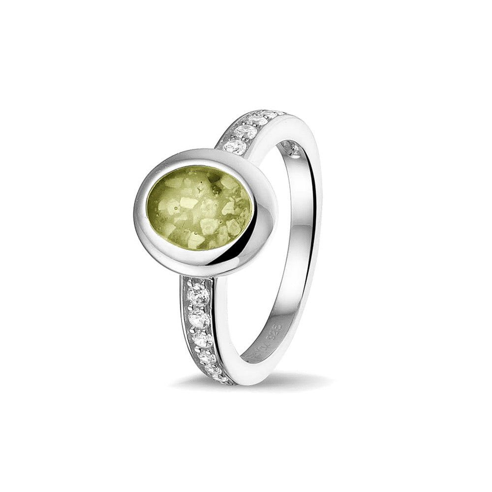Gedenksieraad, ring 3 mm waar aan de ovale bovenzijde zichtbaar as of haar verwerkt wordt. In de bovenste helft van de ringband zijn zirkonia's of diamanten naar keuze gezet. Olive
